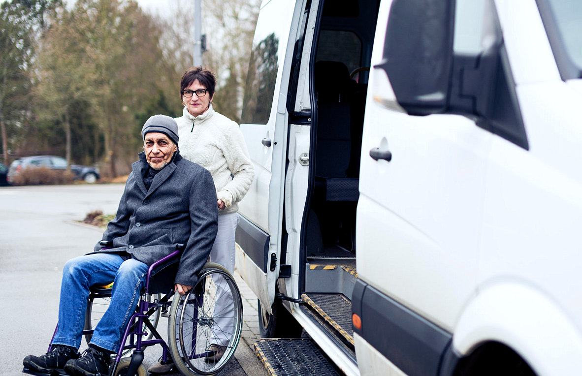 adult woman assisting senior man in wheelchair