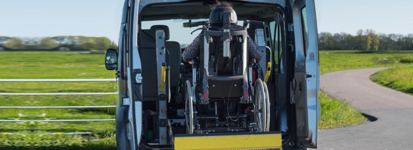 a person in a wheelchair being lifted into non-emergency medical transportation