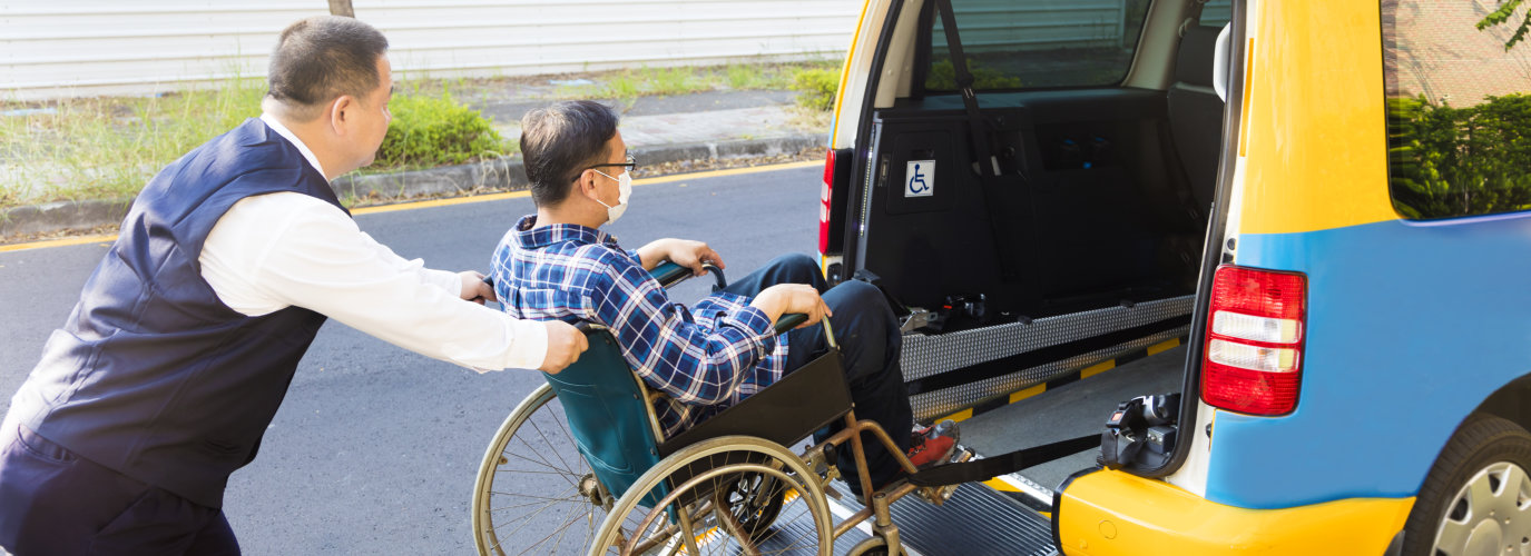 man assisting an elderly man in a wheelchair